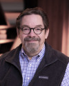 Rob Jackson, Christian life coach and founder of Icebergology™ Coaching Academy, smiling and seated in a warmly lit setting.