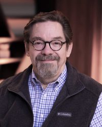 Rob Jackson, Christian life coach and founder of Icebergology™ Coaching Academy, smiling and seated in a warmly lit setting.